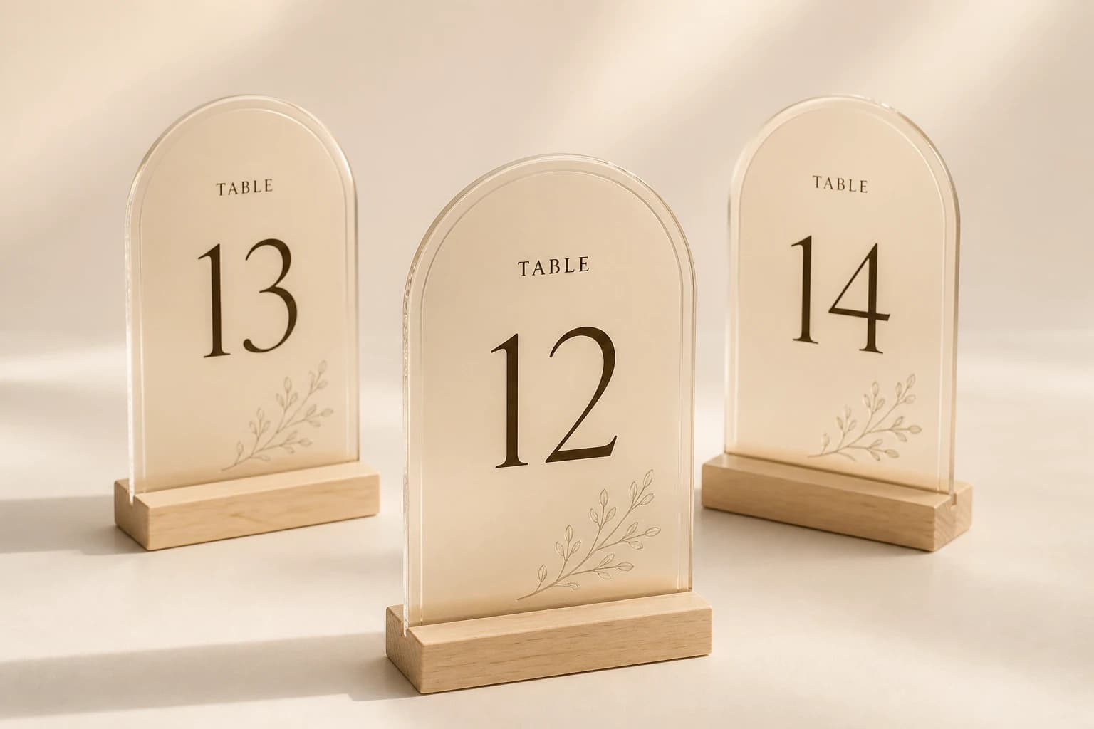 Frosted champagne acrylic wedding table numbers in maple slot bases.